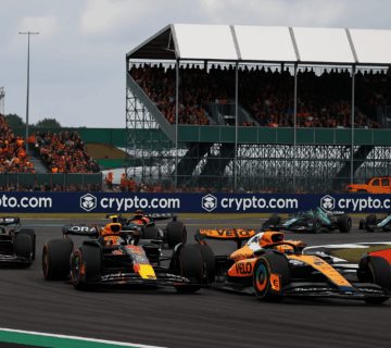 F1 Silverstone 2026 sprint race action with McLaren and Red Bull cars battling on track in front of packed grandstands.